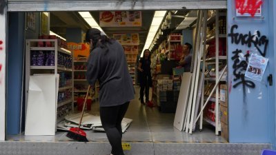 香港佐敦一家零食店，上周六再次被示威者破坏，部分货架被扔出店外，货品散落一地。该店员工隔天回到店里打扫。（中通社）