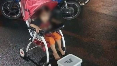 一名坐在婴儿车内的年幼孩童，被父亲推到马路旁行乞，看者心酸。