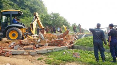 执法人员于周三到峇都加湾Lot248地段采取行动，用神手拆除占用政府地的生基坟地。