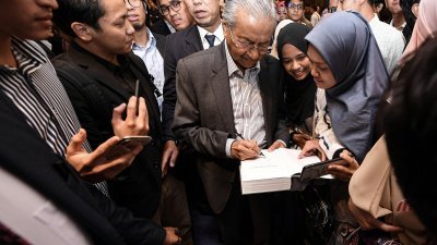 马哈迪（中）周六在日本京都举行的晚宴上，受到旅居日本的大马公民热情欢迎，纷纷向首相索取签名留念。