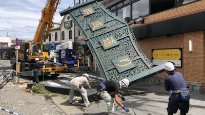 镰仓市的日本铁路镰仓站前商店街入口处设置高约7公尺、写有“御成通”的拱型铁制看板倒塌，部分店家玻璃也有破损。这是工作人员正在拆除倒塌的看板。