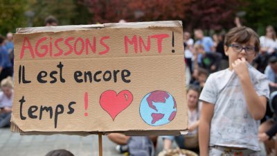 在联合国气候峰会登场前夕，全球多地在周日举行集会或游行，其中在比利时布鲁塞尔，一名男孩站在写著：“现在就行动！仍有时间”的标语牌旁边。