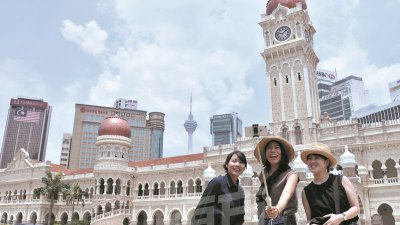 难得见蓝天，吉隆坡周二下午出现晴朗蓝天，游客们在独立广场前留影。深受邻国跨境烟霾严重影响的大马周二各地的烟霾状况大有好转，截至下午4时，全国只有8个地区破百点不健康水平。（摄影：曾钲勤）