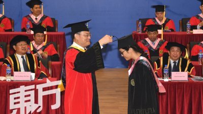 厦门大学大马分校首次举行毕业典礼，该大学校长张荣（站者左）在白天（左）及陈国伟（右）的见证下，颁发毕业证书给毕业生。（摄影：张真甄）