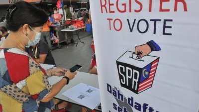 国民可扫描由选民登记服务流动柜台提供的二维码，检查本身的选民资料。（摄影：连国强）