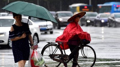 中国首都北京周三迎来今年入汛以来最强暴雨天气，而今年第6号台风“米克拉”的中心周二在福建省漳浦县沿海登陆。这是福建省福州市周二下雨，市民在雨中出行。 （中新社）