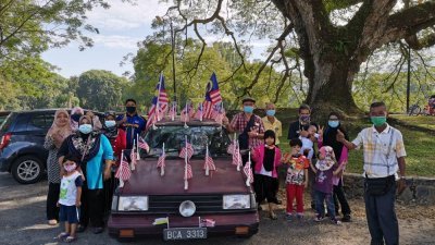 太平湖公园雨树步行街的民众纷纷要求与张挂满国旗的轿车合照留念。