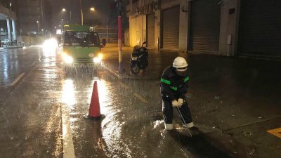 “海高斯”给澳门带来狂风暴雨，造成低洼地区出现水浸现象，市政署工作人员在清理街道积水。（图取自中新社）
