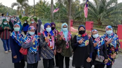 女选民配合国庆日，戴上印有国旗图案的头巾前往投票中心。