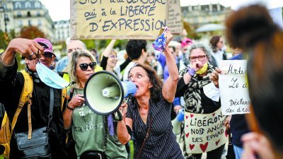 一名妇女于上周六的巴黎示威活动期间，举著写有“停止审查，支持言论自由”标语牌，并用喇叭高呼诉求。示威者还谴责政府强制人们在所有公共场所戴口罩。