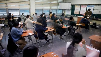 韩国高三的学生周四迎来高考，但不幸碰上新冠肺炎疫情，同时得面对考试和防疫的压力。在首尔的一个考场，考生们在座位上等候开考，每一张桌子都设置了隔板，减低病毒传播。（图取自路透社）