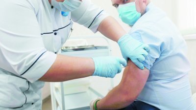 周六在莫斯科展开大规模接种新冠疫苗首日，一间诊断综合诊所内的护士正在为一名男子施打疫苗。(中新社)