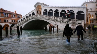 突如其来的大雨再次导致威尼斯淹水，市民涉水在积水的街上行走。（图取自路透社）