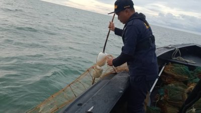 大马海事执法机构人员将可疑浮标捞起时，发现浮标连接著渔民非法设置的“蜈蚣网”。
