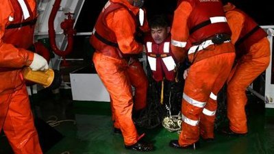 长江口北槽航道水域两艘货柜船相撞，其中一艘沉没，救援员救起遇险船员。