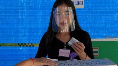 泰国全国76府周日举行地方选举，暖武里府当地一名年轻女子戴上防护面罩，到投票所尽自己的公民义务。（路透社）

