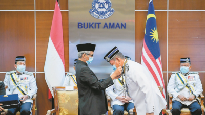 印尼驻马大使赫莫诺（左）在典礼上，亲自为阿都哈密佩戴勋章。