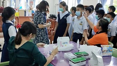 雪州万津启化学校采取防御措施，学校职员为学生戴上口罩。