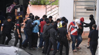 12名猛虎之父99私会党成员周二早上在大批警察押送下抵达巴生地庭，准备面控。