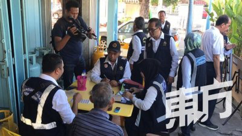 一名食客在饮食店吞云吐雾而被开罚单，站者右3为刘志良。（摄影：魏美琪）