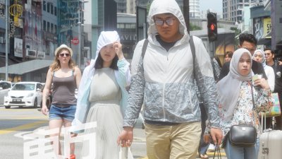 我国近日天气炎热，一些外出的民众纷纷穿上长袖外套或戴上帽子，来抵御紫外线。（摄影：陈启新） 
