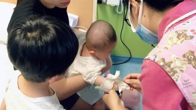 陈宗宏的妻子、4岁大儿子，陪伴著正在接受医护人员注射的3个月大孩子；纵然他是生意人，但家中接连3人患上A型流感，他也大叹吃不消，尤其是幼子的医药费，更高达7000令吉。（图由受访者提供）