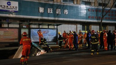 周一晚上，消防队员抵达青海省西宁市的路面塌陷事故现场，进入陷入大坑的公交车内查看情形。（图取自中新社）