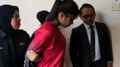 身穿红色马来传统服装的21岁被告努鲁沙米拉涉嫌虐待与致死2岁女儿，周三被带上新山推事庭面控。