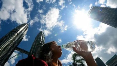 哗，好热！周四在吉隆坡城中城，一名游客一边逛街拍照一边喝水解热。