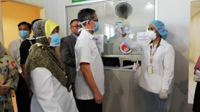 李文材(左2)在怡保机场接受卫医务人员检测体温。