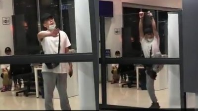 2岁中国女童疑是感染武汉肺炎，其父亲周六晚因不满被机场人员安排在出境室隔离，不时敲打出境室玻璃墙，要求放行。等候卫生局官员到来时，更企图爬越玻璃墙被遏止。（视频截图）