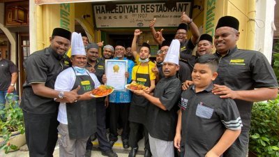 哈密里也餐室第7代传人（左5）与家属及员工们喜庆荣获由大马纪录大全颁发的“全马最老的扁担饭”奖状。