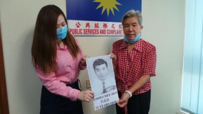 吕莲顺（右）在马华公共服务及投诉部助理张雅欣的陪同下，展示失联哥哥的照片。
