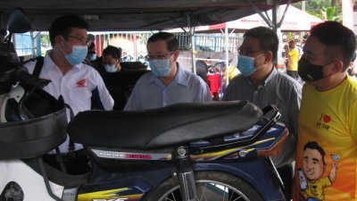 汤川耕平（左起）向林冠英、黄汉伟和黄顺祥讲解本田公司提供的免费维修服务。