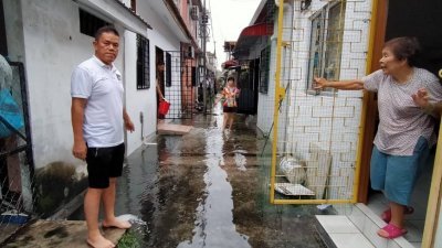 居民向赵启兴（左）投诉，虽然雨停了一段时间，但后巷的水仍未能消退。