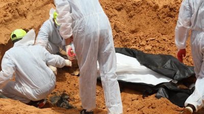 利比亚红新月会以及调查和鉴定失踪人员总局的工作人员，从万人冢内挖掘遗体。