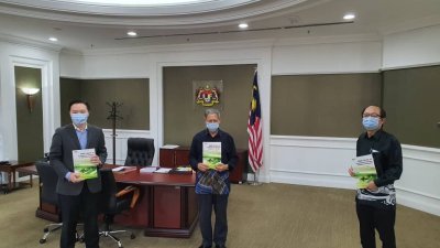翁忠义（左）及陈兆俊（右）提呈《马来西亚疫情条件下的发展政策及选项》报告给慕斯达法（中），并为首相署经济事务捐献3000个口罩。