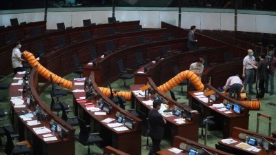 香港立法会周四继续二读辩论《国歌法》，有议员在立法会议会厅内投掷腐烂植物，议会厅紧急疏散人员。消防员和警方到场处理和搜证后，清洁工铺设排气管进行清洁和消毒。（图取自中新社）
