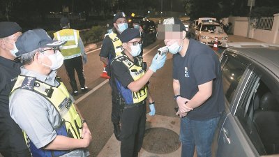 玛兹兰（左）与执勤警员，正对一名车主进行酒精测试。（摄影：曾钲勤）