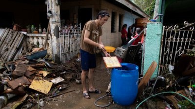 “天鹅”台风侵袭吕宋岛南部，民众受灾严重。一名八打雁市民周一在受到泥石流掩埋的住屋进行清理工作。（图取自路透社）