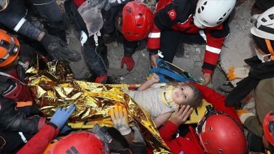 搜救人员周二在伊兹米尔当地的倒塌建筑物内，将获救的4岁女童盖兹京抬出废墟，准备将其送往医院。