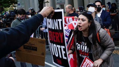 特朗普和拜登的支持者在费城示威，面对特朗普支持者呛声，拜登的支持者将“每一票都要计算”的标语递到对方面前反击。（图取自路透社）