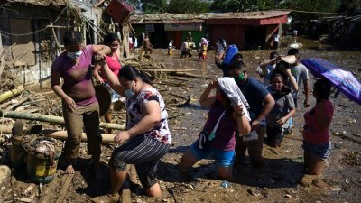 位于菲律宾吕宋岛的黎杀省、罗德里格斯市，亦是此次的洪涝灾区。洪水后，当地居民于周五在充满泥泞的道路上艰难跋涉，准备返回住所。（路透社）