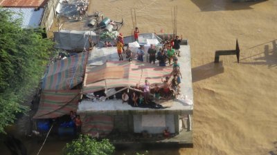 在菲律宾首都马尼拉以北的卡加延谷，成千上万户被洪水淹没，灾民在屋顶上等待求救。（菲律宾海岸警卫队/路透社）