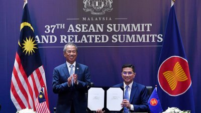 首相慕尤丁（左）周日在第37届东盟峰会与相关会议上，见证阿兹敏（右）代表我国签署“区域全面经济伙伴关系协定”（RCEP）。