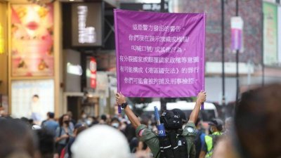 警方高举紫旗警告大喊口号的市民，有可能违反《港区国安法》。