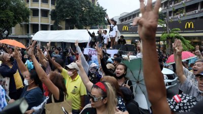 支持民主的抗议者周二在泰国首都曼谷聚集，并趁王室车队经过时，高举反政府运动的三指手势。