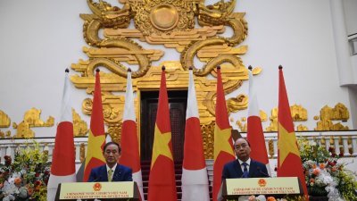 日本首相菅义伟（左）于周一在越南政府办公厅与越南总理阮春福会晤，两人随即在新闻发布会上发表讲话。(路透社)