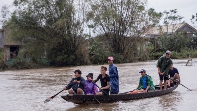 越南承天-顺化省Quang An镇居民，周二划船至一个领取救济品的地点，以便将救济品运送给其他受暴雨洪涝影响的居民。
