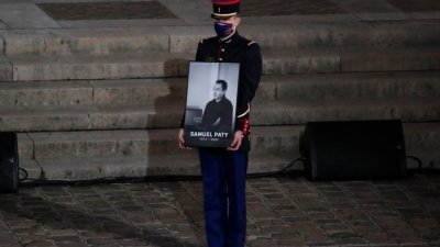 在索邦大学举行的追思会现场，一名法国共和国卫队成员手捧帕蒂的遗像。